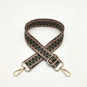 Detail of woven bag strap with pink geometric diamond pattern and gold metal hooks
