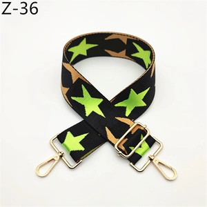 Detail of adjustable bag strap featuring green stars and gold metal hardware
