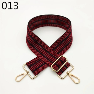 Close-up of a wide red and black geometric woven bag strap with golden lobster clasps
