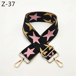 Detail of adjustable wide bag strap with pink and gold stars on black woven fabric