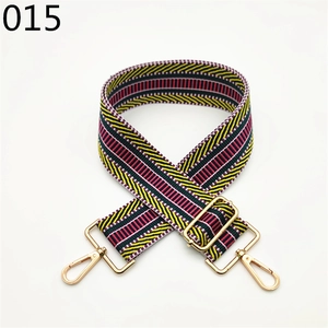 Close-up of a wide woven bag strap in yellow and red with gold lobster clasps