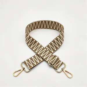 Close-up of brown and white herringbone woven strap with adjustable gold metal buckle