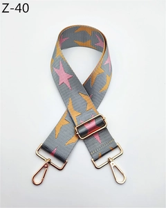 Detail of gray bag strap with pink star pattern and adjustable gold metal buckles