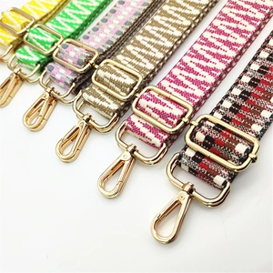 Detail view of woven bag straps with diverse patterns and shiny gold metal swivel hooks