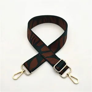Détail de la bandoulière tissée à motif de feuilles vert et marron avec fermoir doré