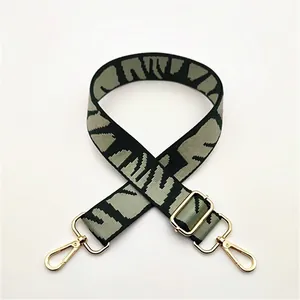 Détail de la bandoulière tissée réglable avec motif géométrique vert et crochets dorés