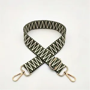 Détail de la bandoulière tissée verte et beige avec mousquetons en métal doré et boucle