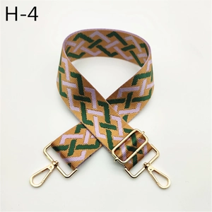 Detail view of woven bag strap with purple and green geometric wave patterns and gold buckle