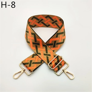 Macro detail of adjustable woven geometric strap with orange accents and gold buckles