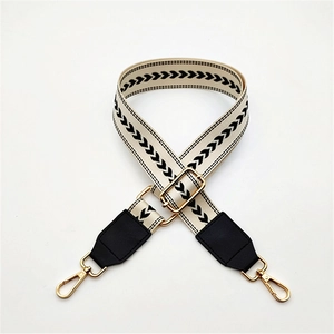 Close-up of adjustable cream webbing strap with black heart patterns and gold hardware