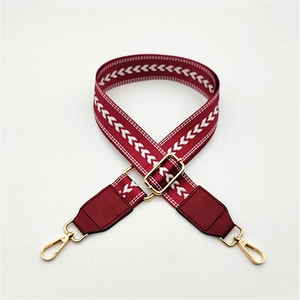 Close-up of burgundy herringbone patterned bag strap with golden metal lobster clasps