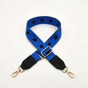 Detail of adjustable blue strap with black star patterns and gold metal buckles