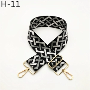 Close-up of geometric woven shoulder strap in black, gray, and white with gold metal hooks