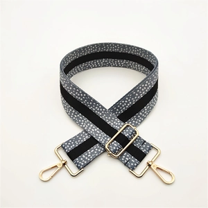Close-up of adjustable wide shoulder strap with grey white polka dots and gold metal buckles