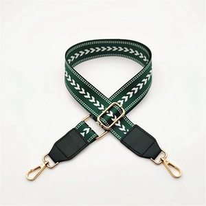 Close-up of dark green canvas shoulder strap with white herringbone pattern and gold hardware