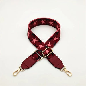 Detail of adjustable wide purse strap with burgundy stars and gold metal buckles