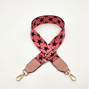 Detail of adjustable pink PU leather strap with black star patterns and gold metal hooks