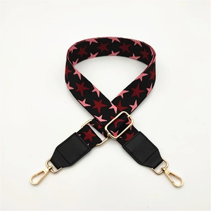 Detail of adjustable bag strap with red and pink star pattern and gold metal lobster clasps