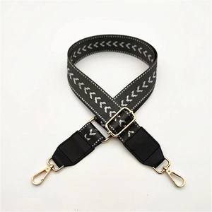 Detail of adjustable black and white herringbone bag strap with golden lobster clasps