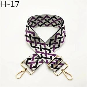 Detail view of woven geometric wide bag strap with gold metal hooks and purple plaid pattern