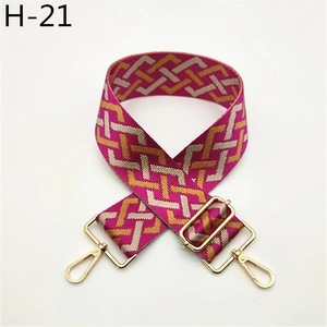 Macro detail of geometric magenta woven bag strap with golden metal swivel hooks