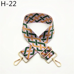 Close-up of geometric woven shoulder strap with gold metal hooks and adjustable hardware