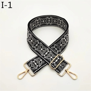Close-up of adjustable woven bag strap with snowflake pattern and gold metal buckles