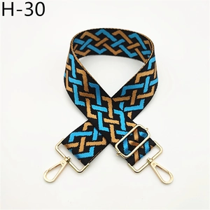Detail of wide woven strap with blue and brown geometric patterns and gold metal clasps