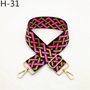 Close-up of pink, gold, and black geometric woven bag strap with golden metal hardware