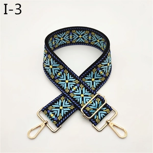Detail of widened ethnic jacquard bag strap with blue snowflake patterns and gold hardware