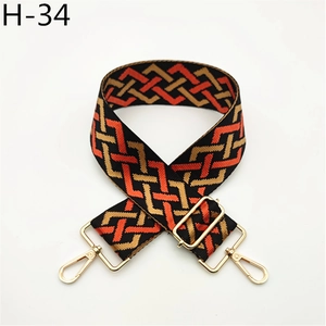 Detail view of retro geometric wide bag strap with orange and gold weave and metal hooks