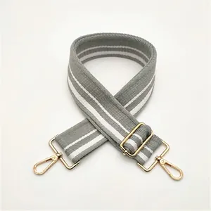 Detail of adjustable gray and white striped handbag strap with gold metal hardware hooks