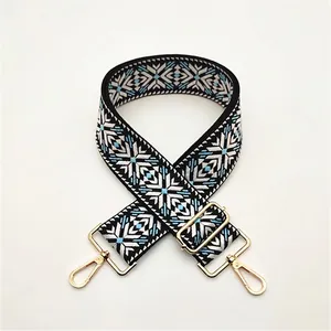 Detail of adjustable wide bag strap with geometric snowflake jacquard and gold hardware
