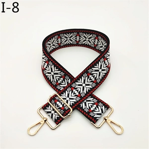 Detail of wide jacquard bag strap with red snowflake pattern and gold metal hooks
