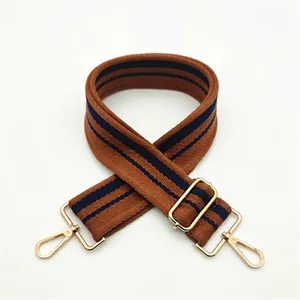 Close-up of adjustable striped brown and blue bag strap with golden metal swivel hooks
