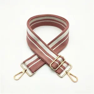 Macro detail of pink and white striped cotton bag strap with golden lobster clasps