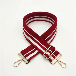 Detail of red and white striped bag strap with golden metal buckles and spring hooks