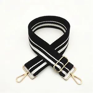 Detail of wide black and white striped canvas strap with adjustable gold metal buckle