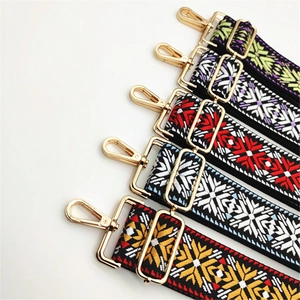 Detail view of ethnic embroidery purse straps with colorful geometric patterns and gold metal hooks