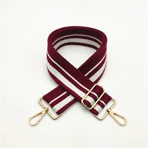 Detail of adjustable burgundy and white striped wide strap with gold-tone metal hardware