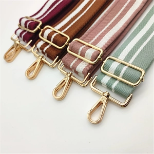 Close-up of adjustable striped canvas bag straps with gold metal hooks and sliding buckles