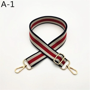 Detail view of red white and blue striped bag strap with gold metal hooks and buckle