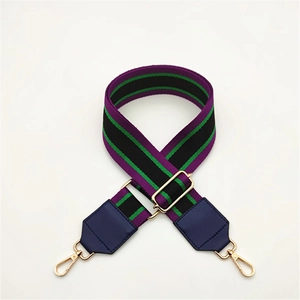 Detail of adjustable woven striped bag strap with purple green colors and gold metal hooks