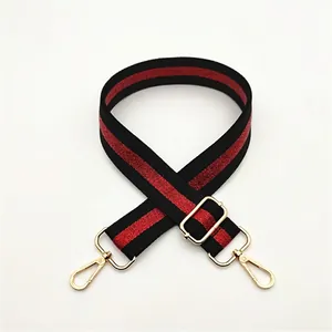 Detail of adjustable black and red striped bag strap with gold metal lobster clasps
