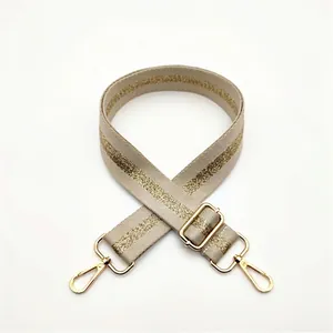 Close-up of beige woven adjustable shoulder strap with gold glitter and lobster clasps