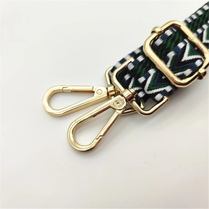Detail of bohemian woven bag strap with geometric patterns and gold metal buckles