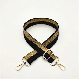 Detail of adjustable black and gold shimmering bag strap with metallic swivel hooks