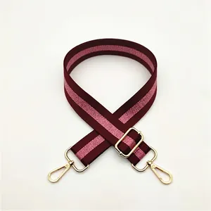 Detail view of burgundy and pink striped bag strap with shiny gold metal lobster clasps