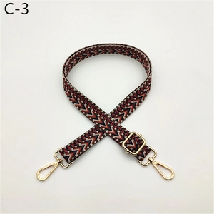 Detail of geometric woven bag strap with golden metal swivel hooks and adjuster