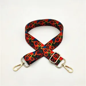Close-up of ethnic style red shoulder strap with colorful floral patterns and gold hooks